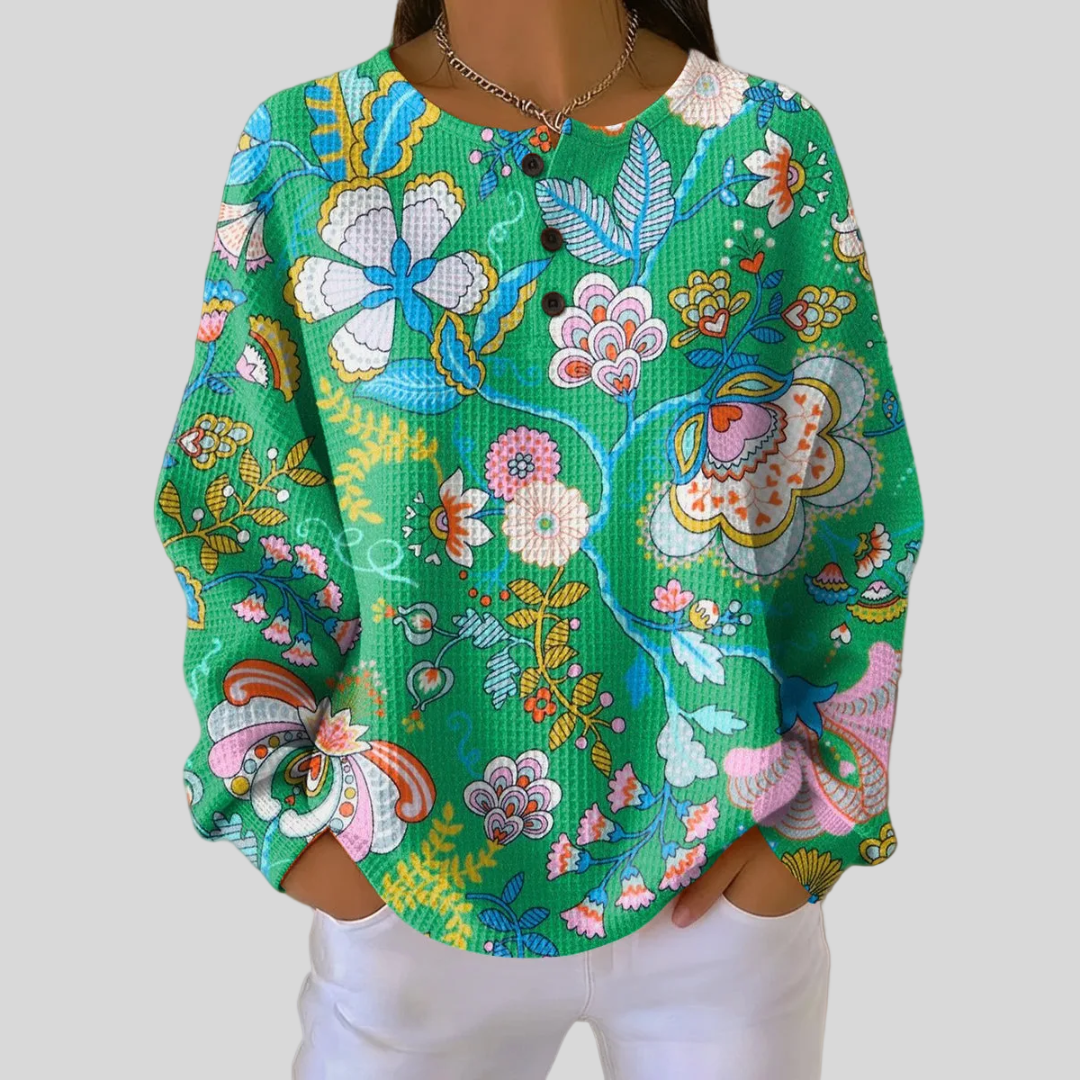 Éliane – Grüene Pullover mit Folk-Blüemli